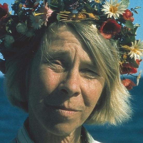 Tove Jansson med blomsterkrans foran havet