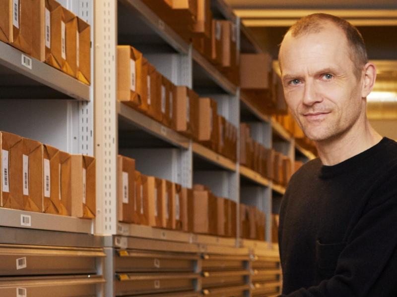 Adam Jon Kronegh ved siden af reoler med arkivkasser