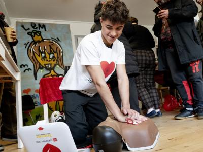 Dreng giver hjertemassage til førstehjælpsdukke.