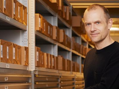 Adam Jon Kronegh ved siden af reoler med arkivkasser