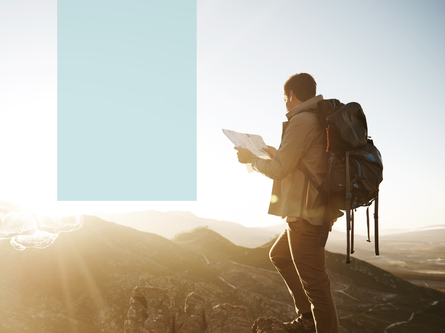 Mand med rygsæk og kort på toppen af bakke i lav sol